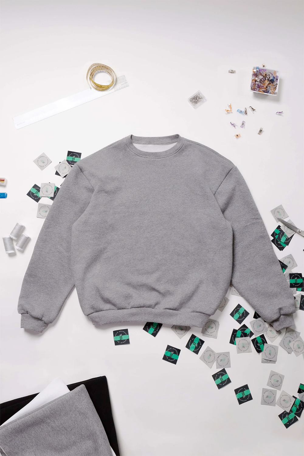 Grey sweatshirt on a white background with scattered items