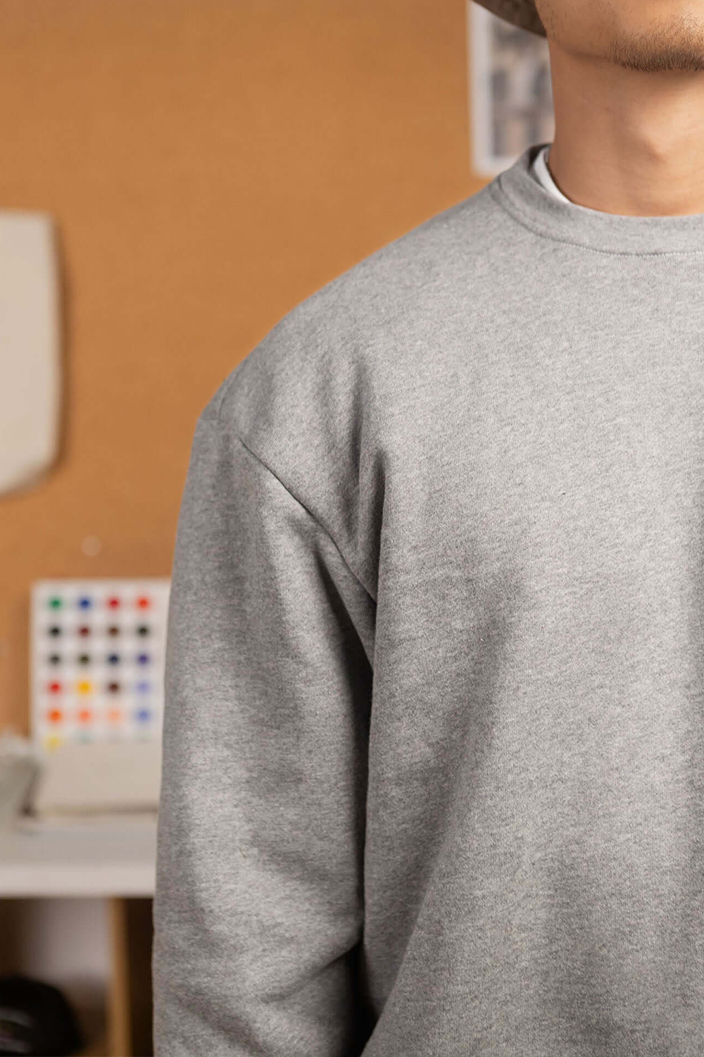 Person wearing a grey sweatshirt with a blurred indoor background