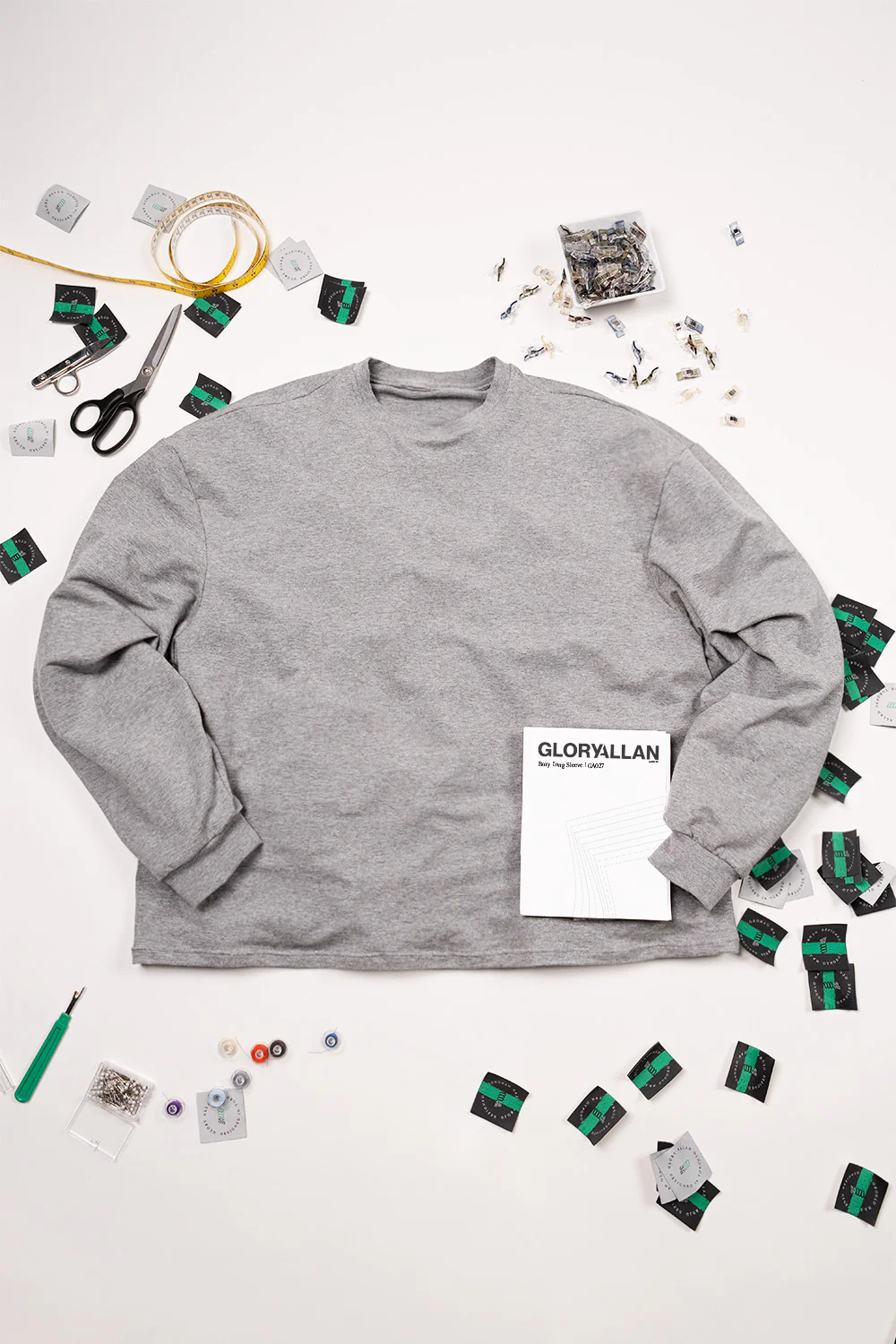 Grey boxy long sleeve shirt on a white background with decorative items.