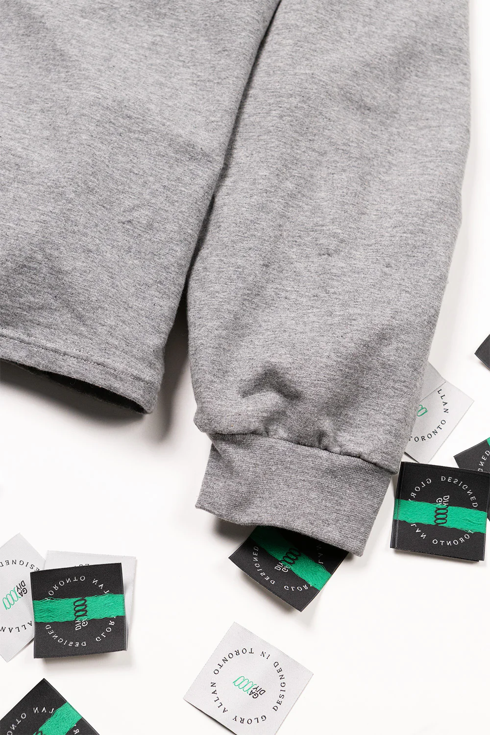 Grey boxy long sleeve with brand labels on a white background