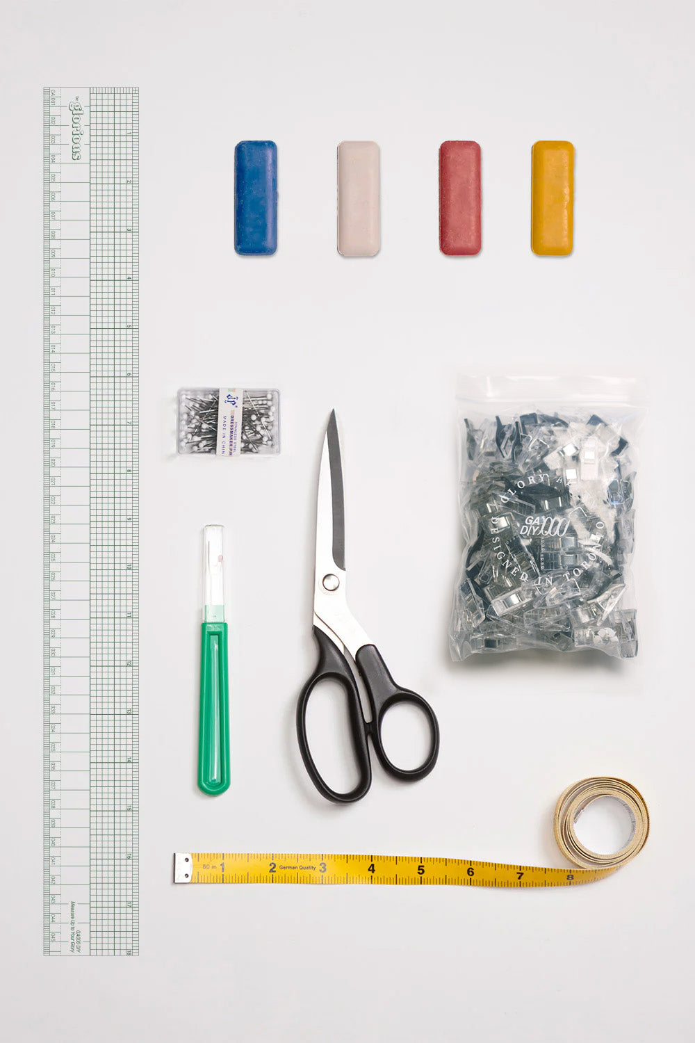 Assorted craft supplies including scissors, tape measure, ruler, and small items on a white background