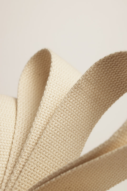 Curved straps of natural-beige 100% cotton webbing.