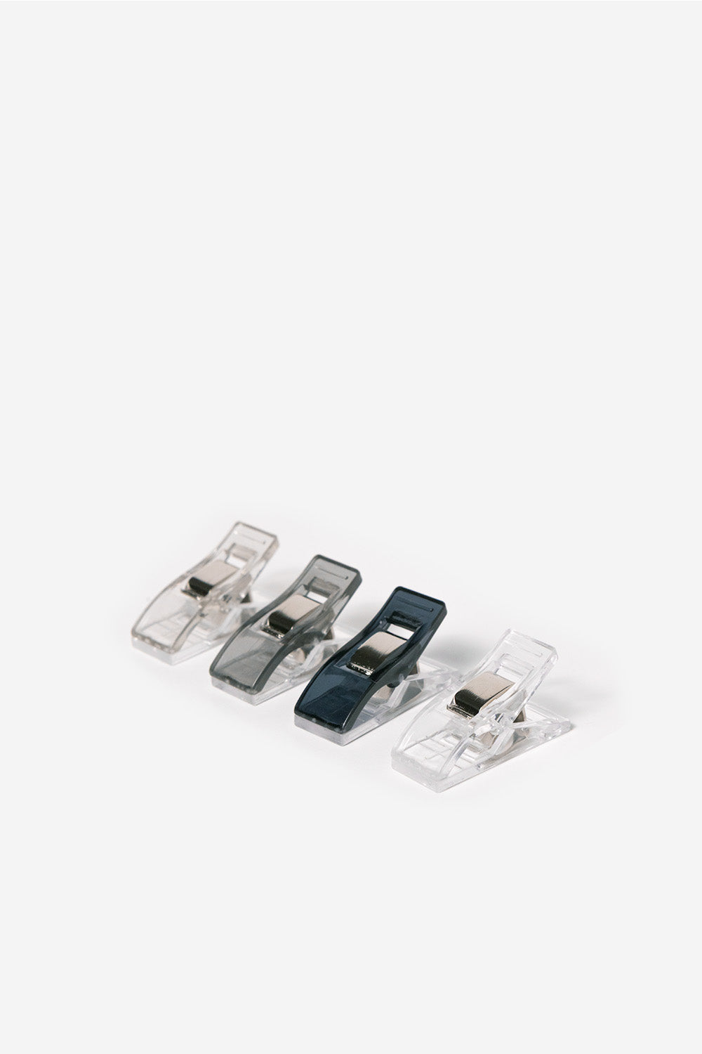 Set of four plastic clips on a white background. Colors of Navy, grey, light grey and clear.