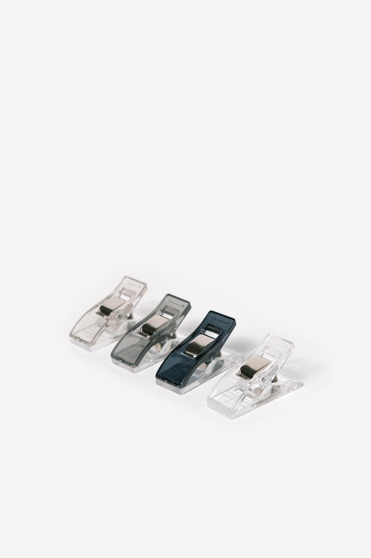 Set of four plastic clips on a white background. Colors of Navy, grey, light grey and clear.